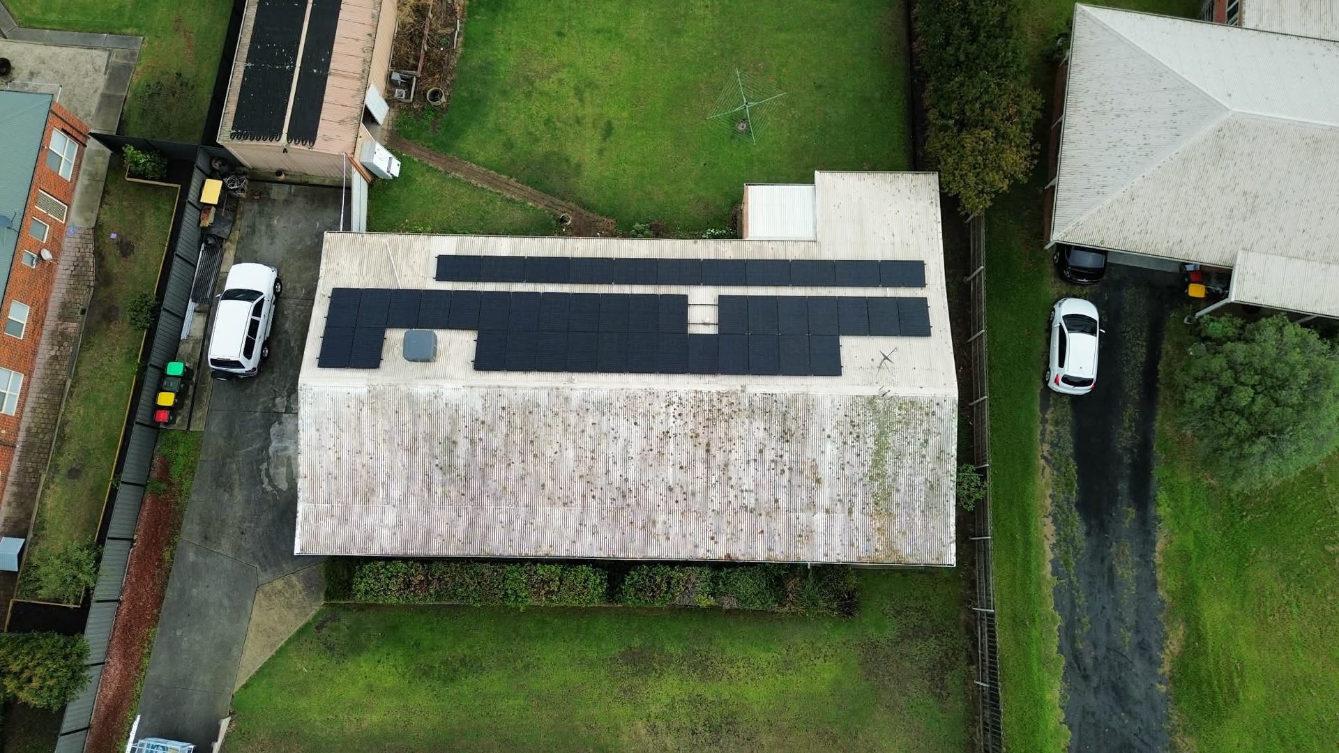Aerial drone view of suburban home with moss-speckled metal roof — before clean