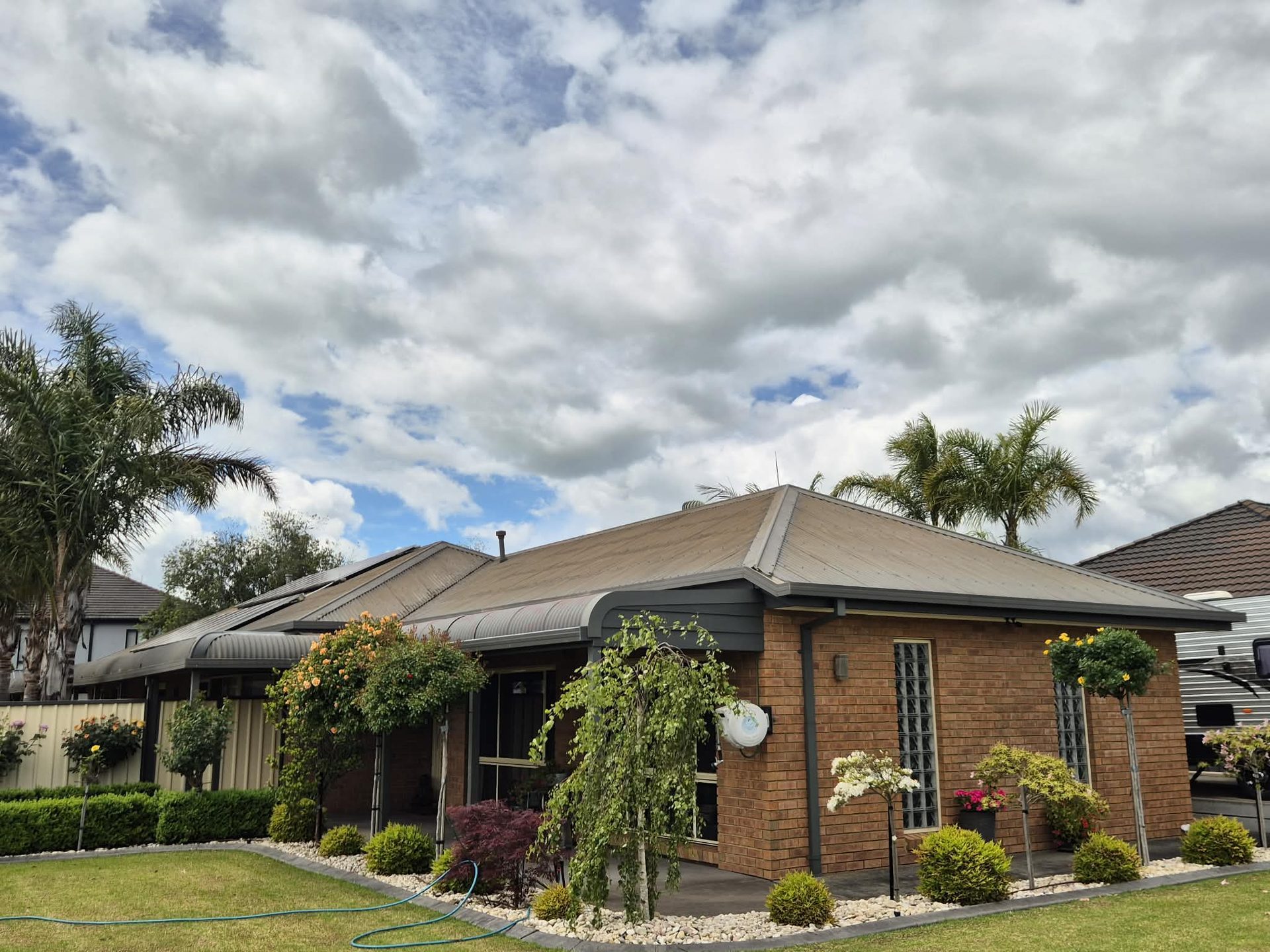 Suburban brick home with faded khaki Colorbond — before